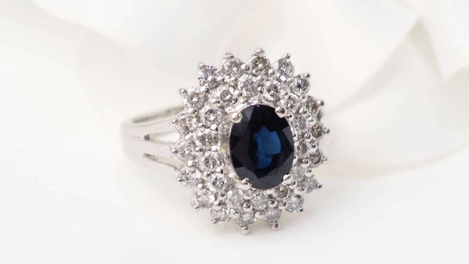 Bague entourage en or blanc centrée d'un saphir ovale entouré de diamants