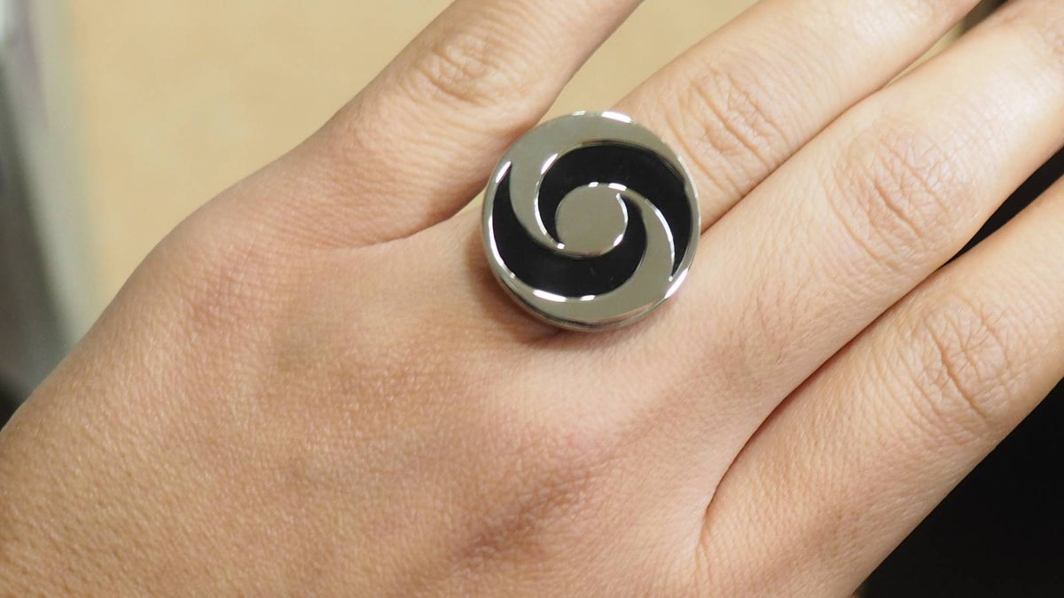 Bague L'Aurore Bulgari Yin Yang en or blanc et acier avec motif rotatif en onyx noir portée sur un doigt