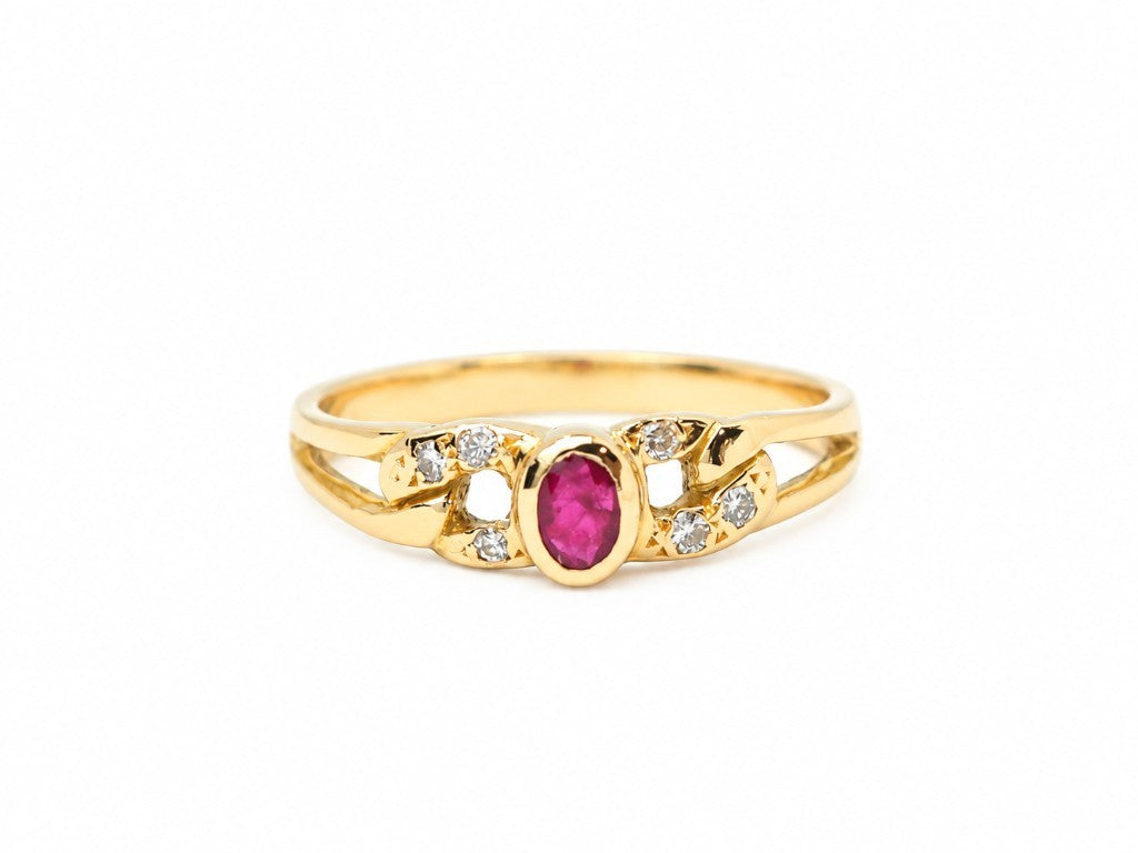 Bague L'Aurore en or jaune avec un rubis ovale central et des diamants sertis sur un anneau ajouré élégant.