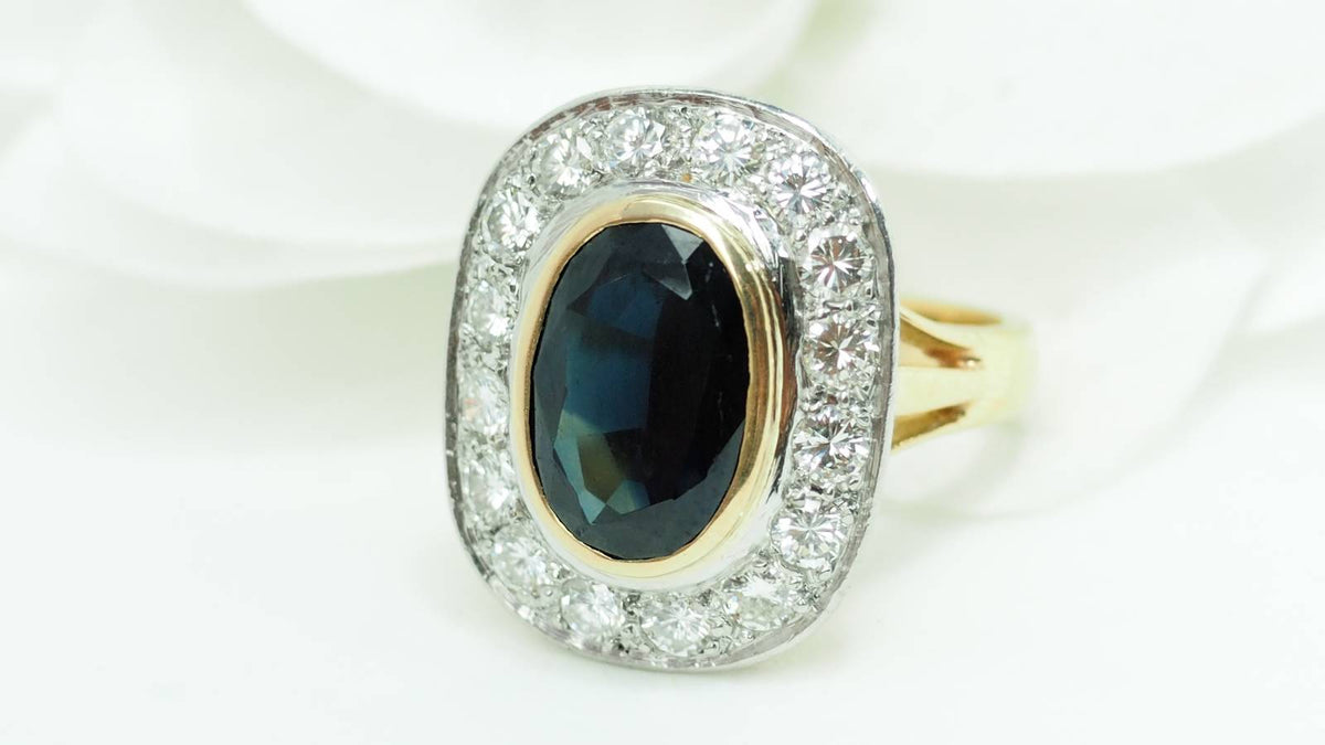 Bague pompadour L'Aurore en or jaune et platine avec un saphir ovale central entouré de diamants étincelants