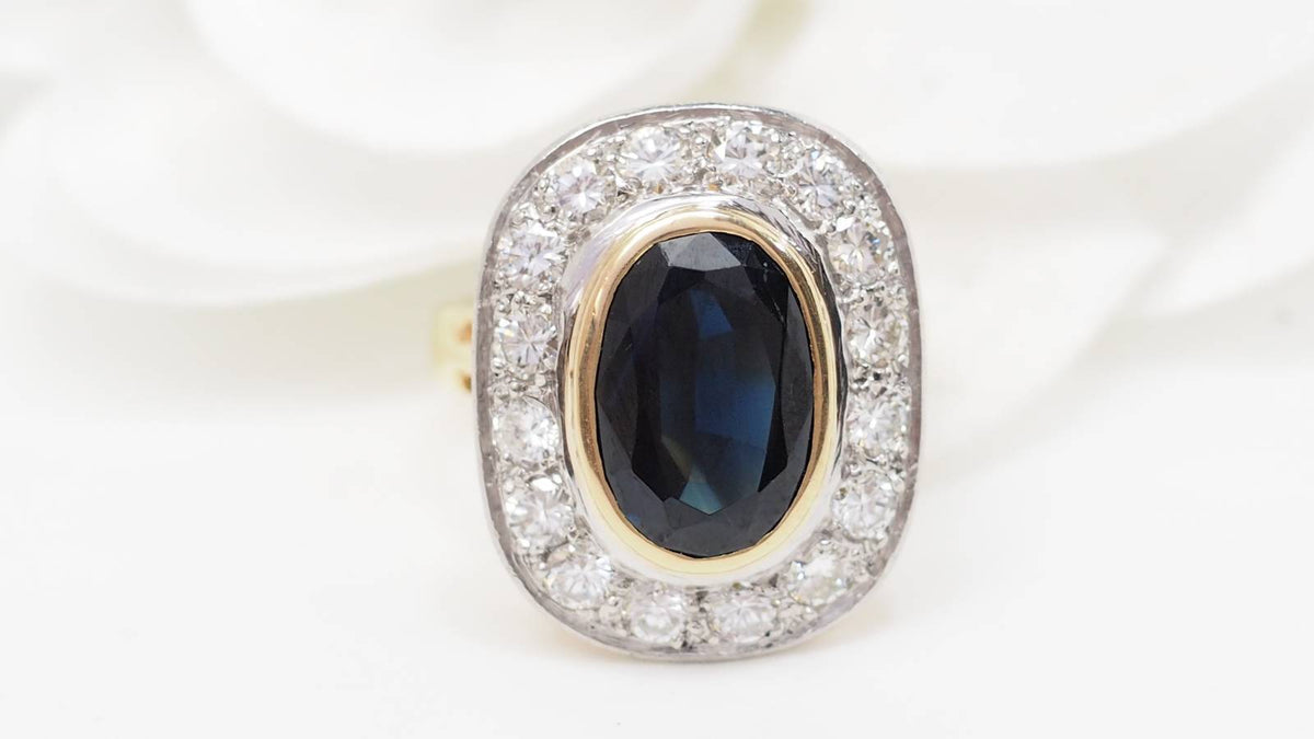 Bague pompadour L'Aurore en or jaune et platine avec un saphir ovale central entouré de diamants étincelants