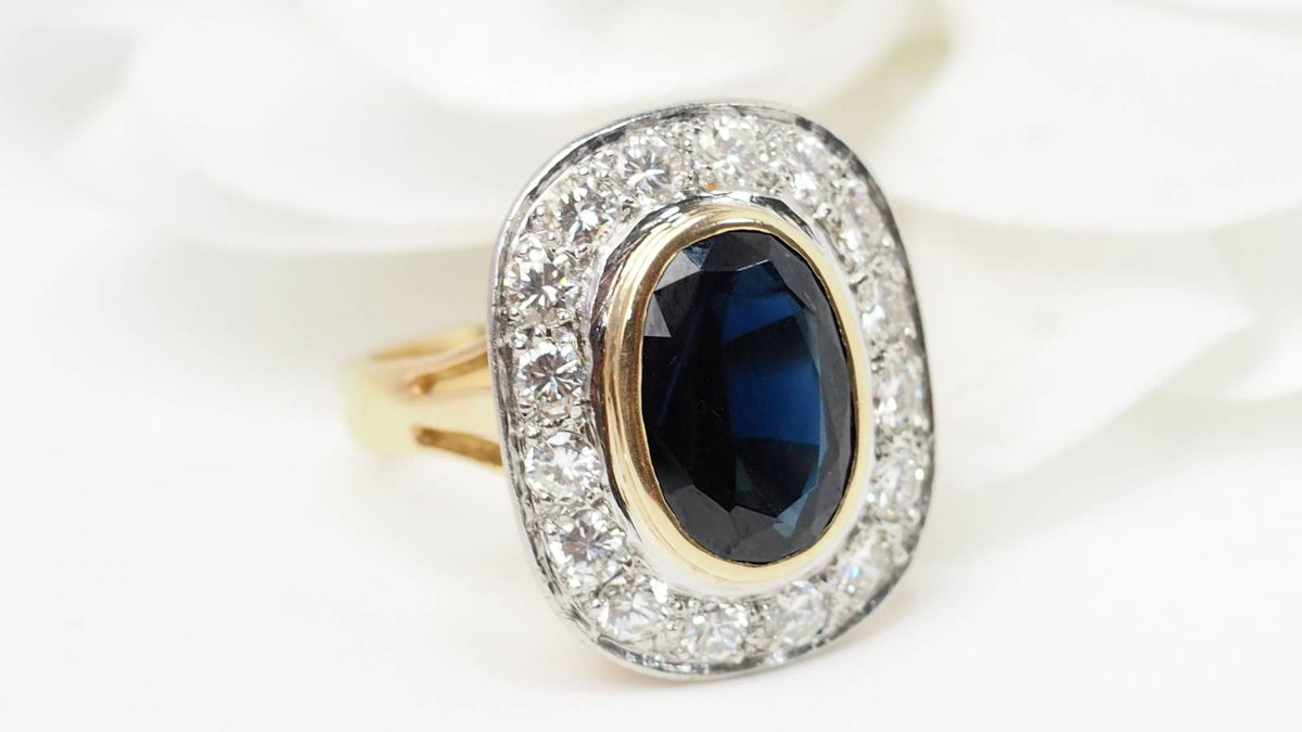 Bague pompadour L'Aurore en or jaune et platine avec un saphir ovale entouré de diamants étincelants