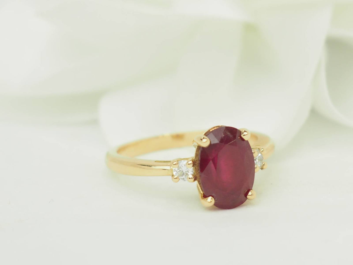 Bague L'Aurore en or jaune 18kt avec un rubis ovale de 2,59 carats et deux diamants taille brillant sur les côtés