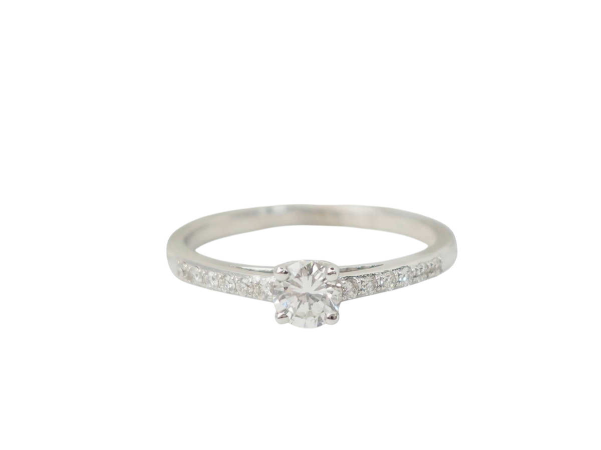 Bague solitaire L'Aurore en or blanc 18 carats avec diamant central 0,30 ct et diamants sur l'anneau