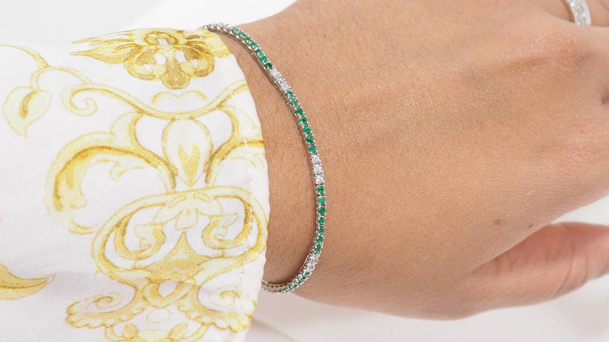 Bracelet rivière L'Aurore en or blanc 18k serti d'émeraudes et de diamants brillants porté au poignet