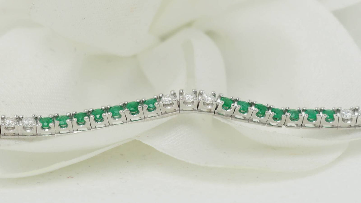 Bracelet rivière L'Aurore en or blanc 18k serti d'émeraudes et de diamants taille brillant sur fond blanc