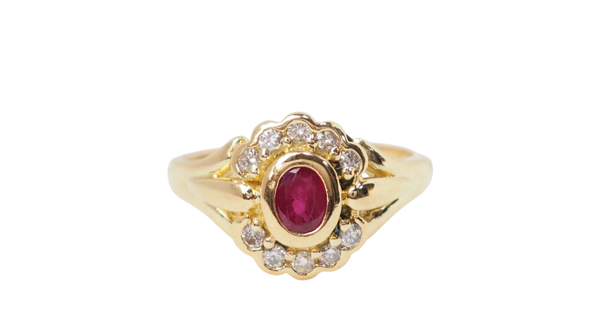 Bague marguerite vintage L'Aurore en or jaune 18kt, sertie d'un rubis ovale central entouré de diamants brillants.