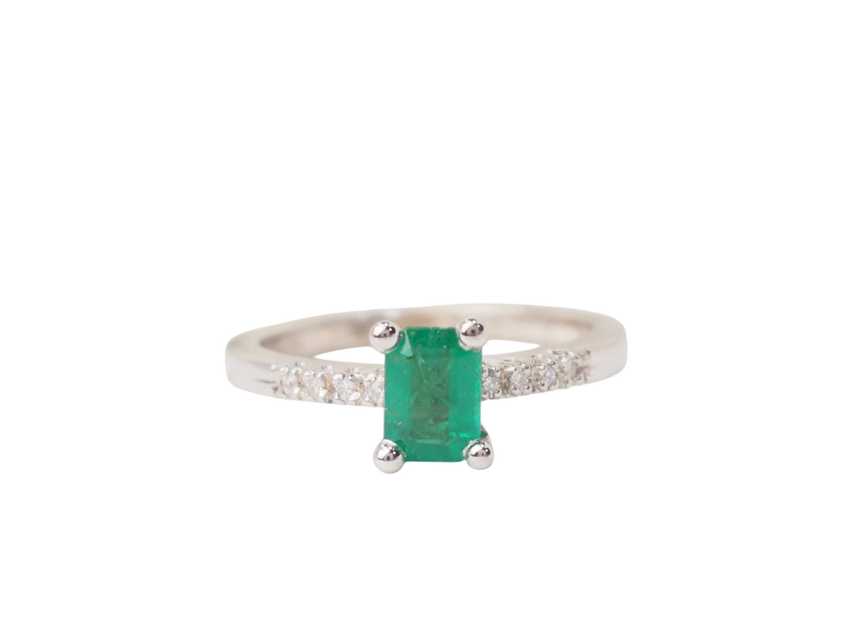 Bague solitaire L'Aurore en or blanc avec émeraude rectangulaire sertie griffes et diamants sur l'anneau