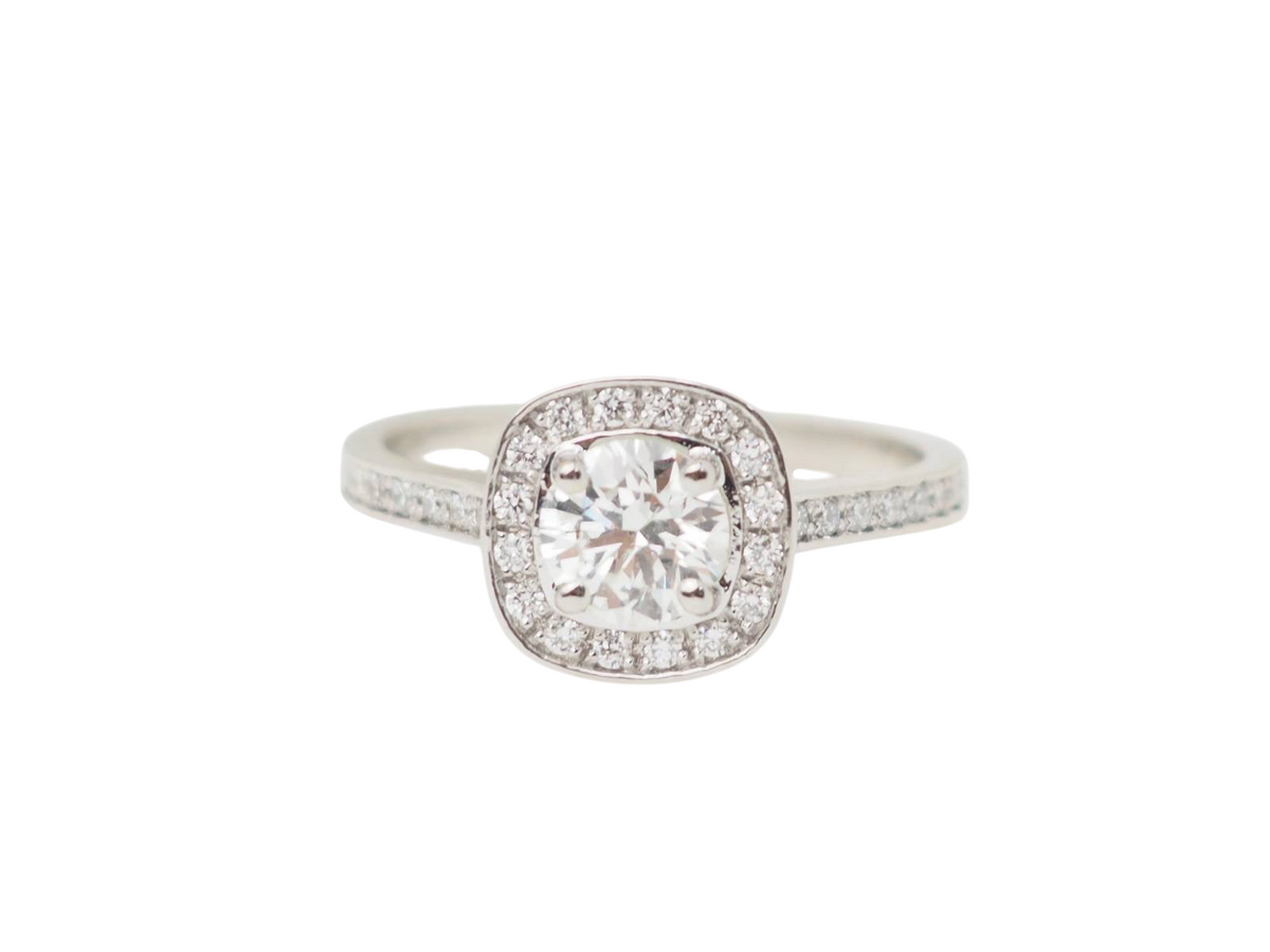 Bague solitaire L'Aurore en or blanc 18k avec diamant central 0.68ct et entourage halo de diamants brillants