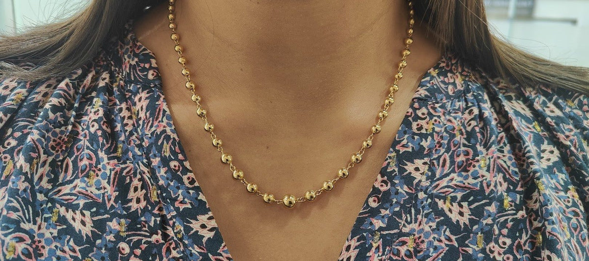 Collier marseillais vintage en or jaune 18 carats avec boules graduées porté par une femme, L'Aurore