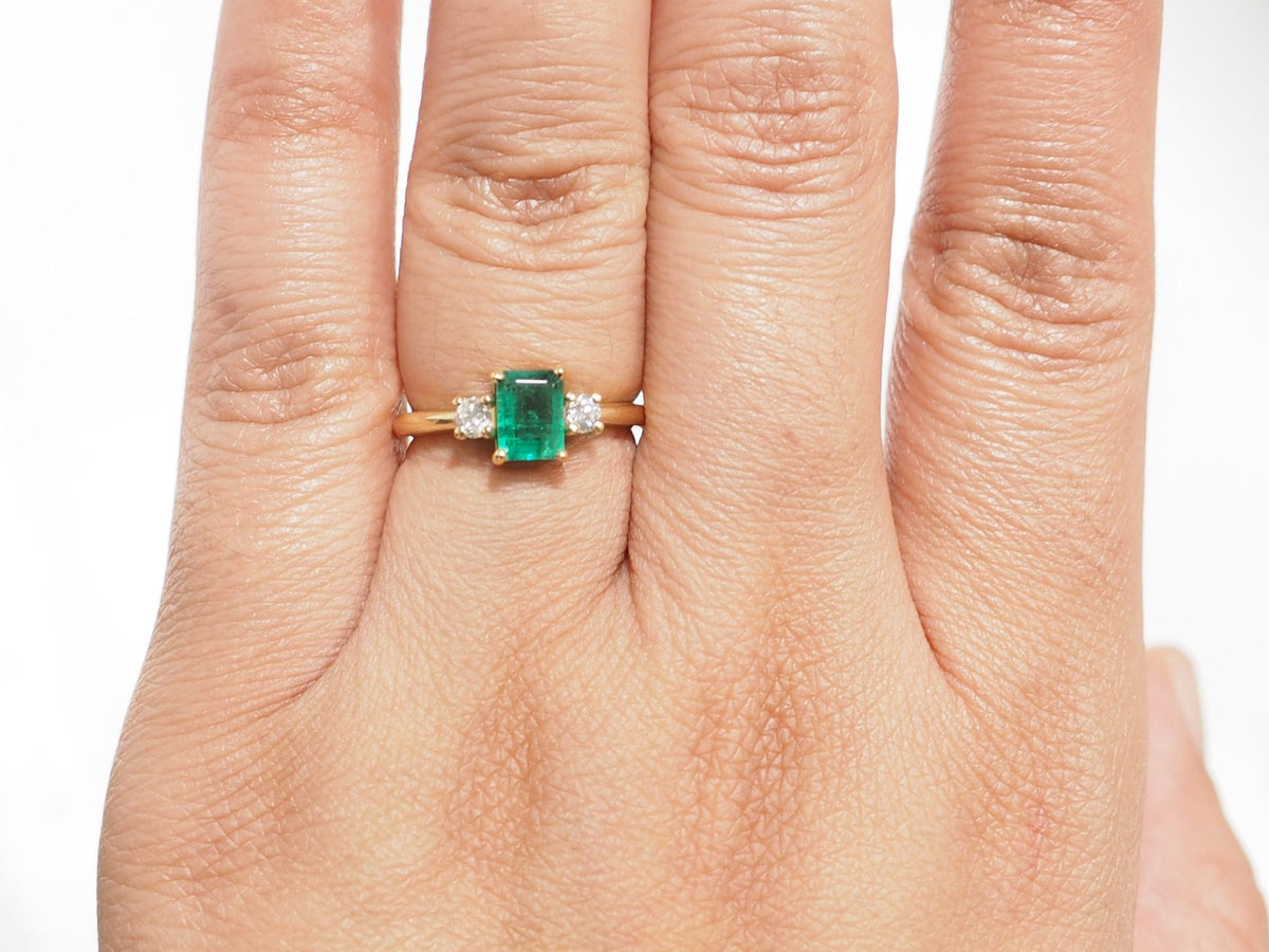 Bague L'Aurore en or jaune 18kt avec émeraude de Zambie 0,85ct et diamants taille brillant portée au doigt