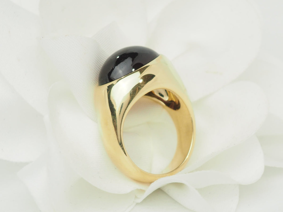 Bague vintage L'Aurore Pomellato en or jaune 18 carats avec un grenat cabochon sombre sur fond floral blanc