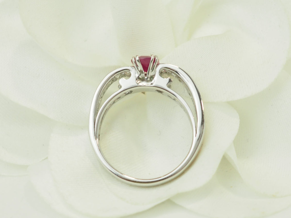 Bague L'Aurore en or blanc 18 carats avec rubis central de 1,30 carat et diamants, vue de profil sur fond floral.