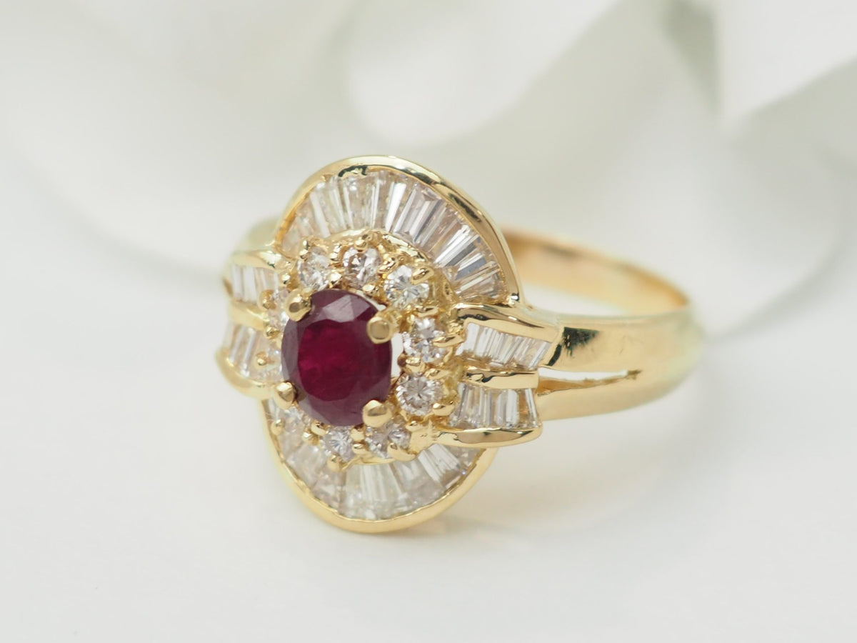 Bague jupe vintage L'Aurore en or jaune 18k, ornée d'un rubis central entouré de diamants brillants et baguettes.