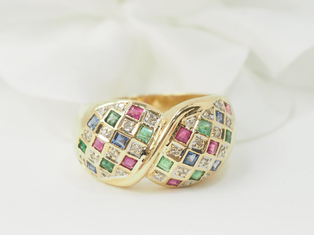 Bague vintage L'Aurore en or jaune 18k pavée de diamants, émeraudes, saphirs et rubis sur fond blanc