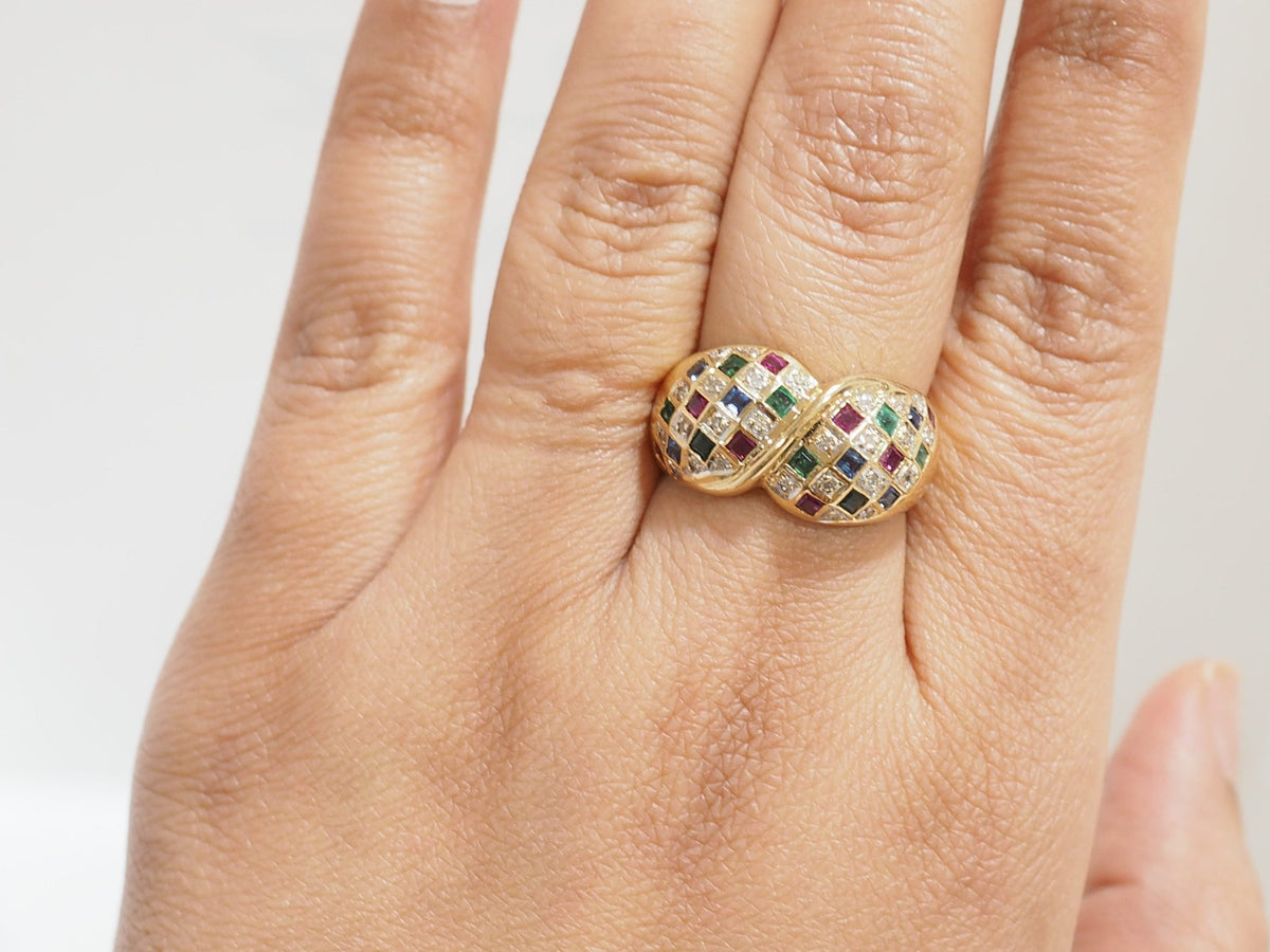 Bague vintage L'Aurore en or jaune 18kt pavée de diamants, émeraudes, saphirs et rubis portée sur un doigt