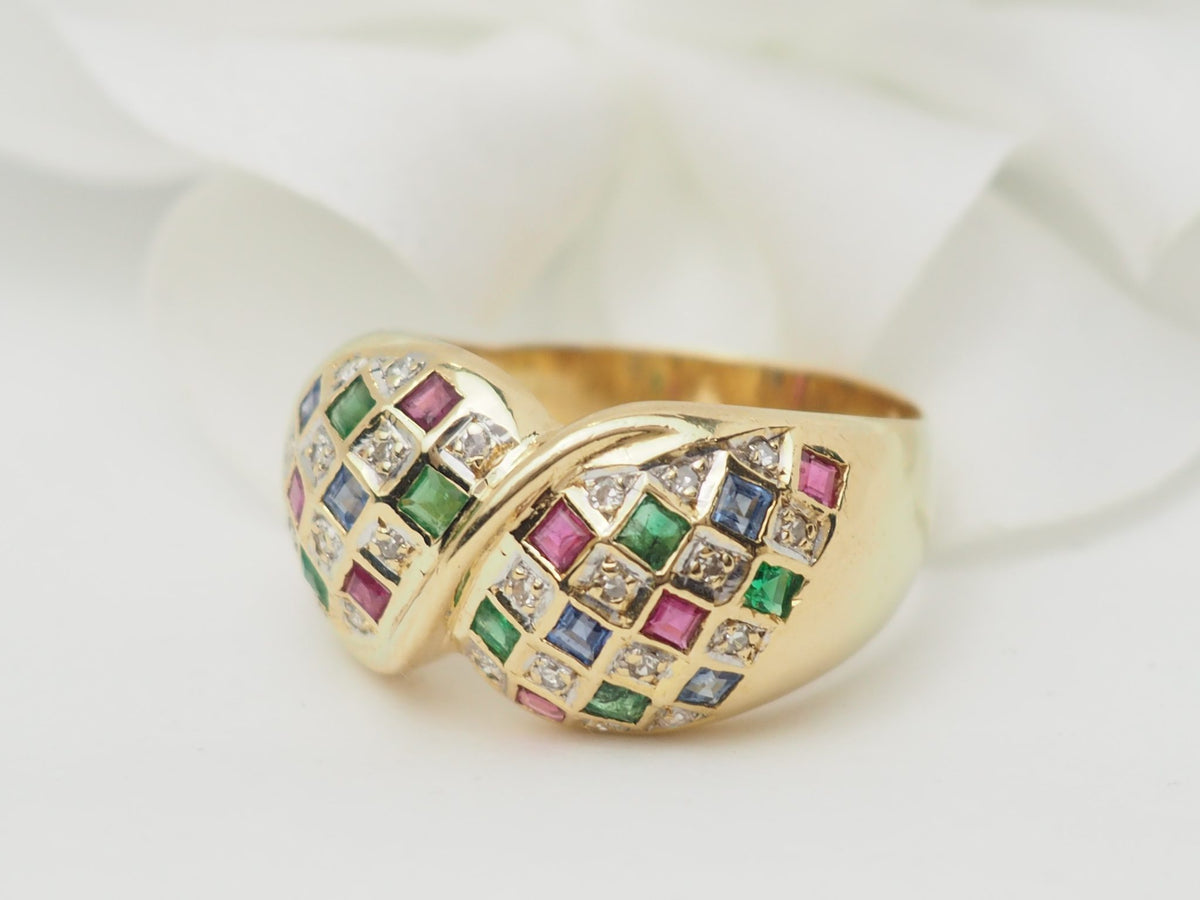 Bague vintage L'Aurore en or jaune 18kt pavée de diamants, émeraudes, saphirs et rubis sur fond blanc