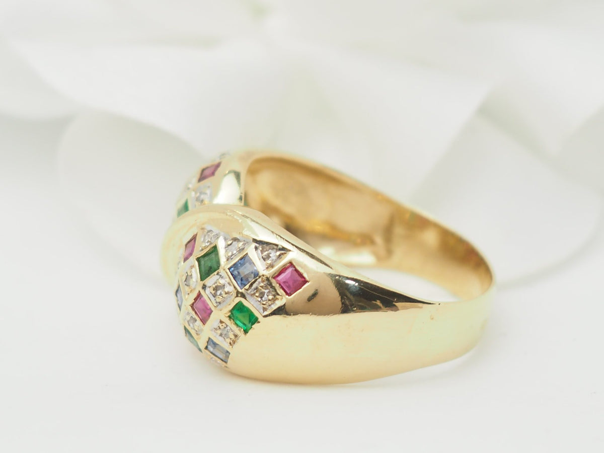 Bague vintage L'Aurore en or jaune 18kt avec pavage de diamants, émeraudes, saphirs et rubis sur fond blanc