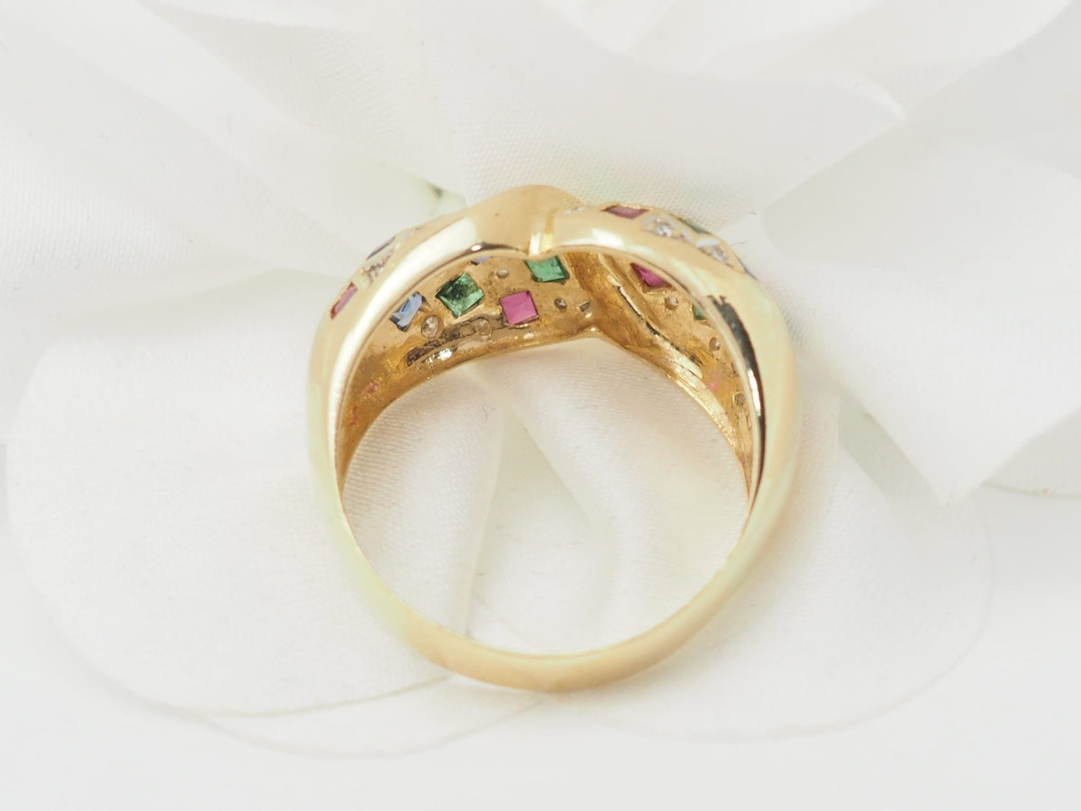 Bague vintage L'Aurore en or jaune 18kt avec pavage de diamants, émeraudes, saphirs et rubis sur fond blanc