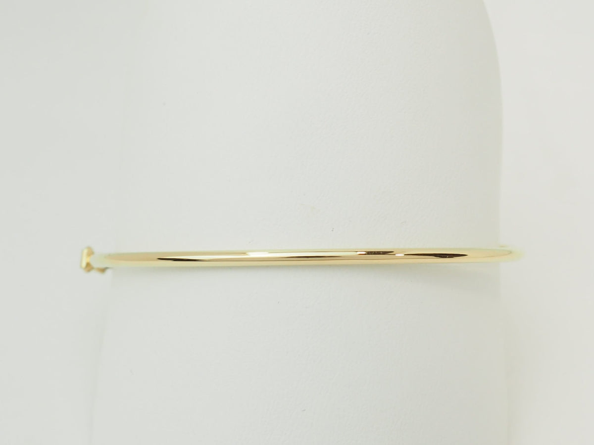 Bracelet jonc flexible L'Aurore en or jaune 18 carats avec fermoir de sécurité sur support blanc