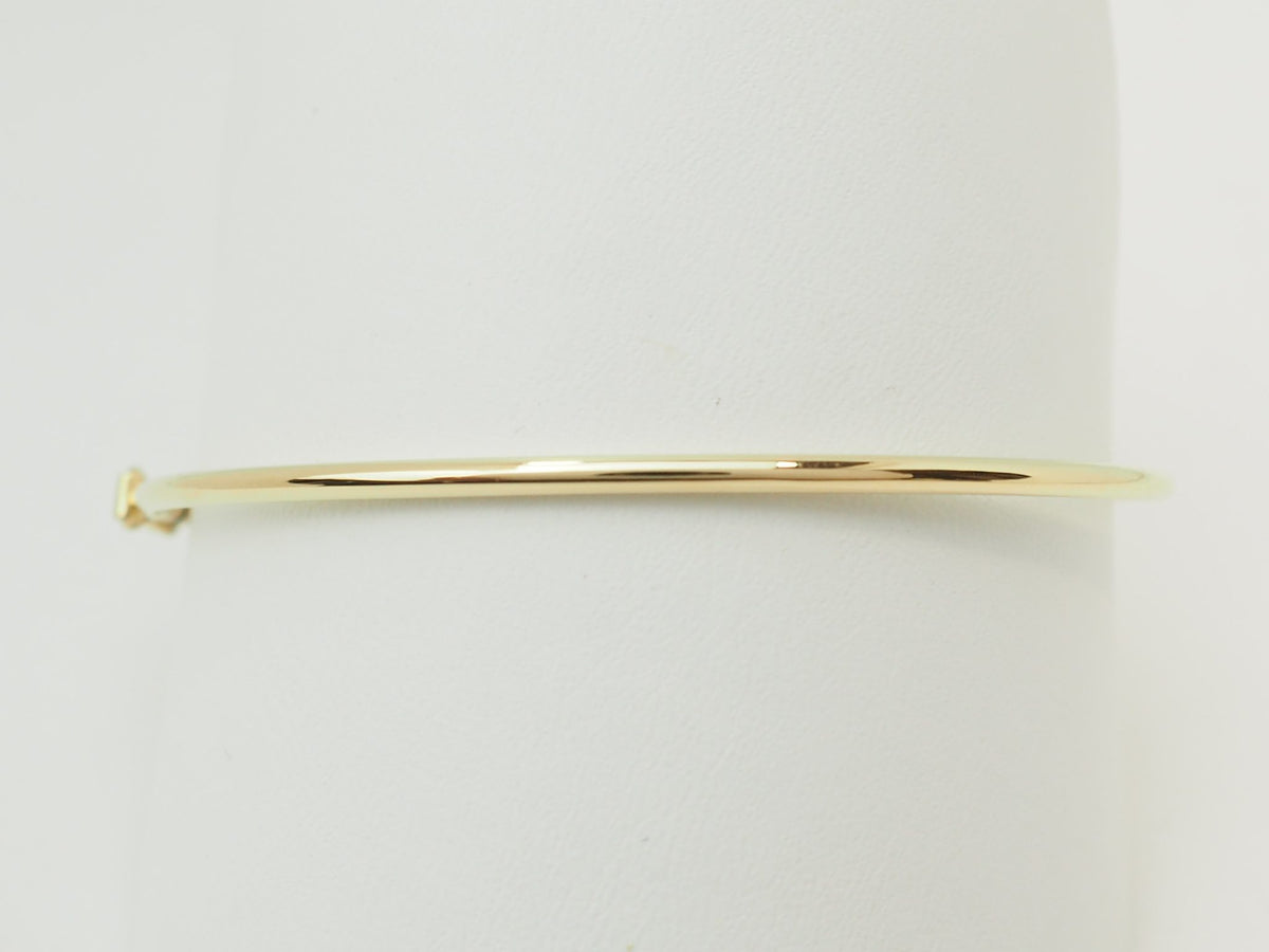 Bracelet jonc flexible L'Aurore en or jaune 18 carats avec fermoir de sécurité sur support blanc
