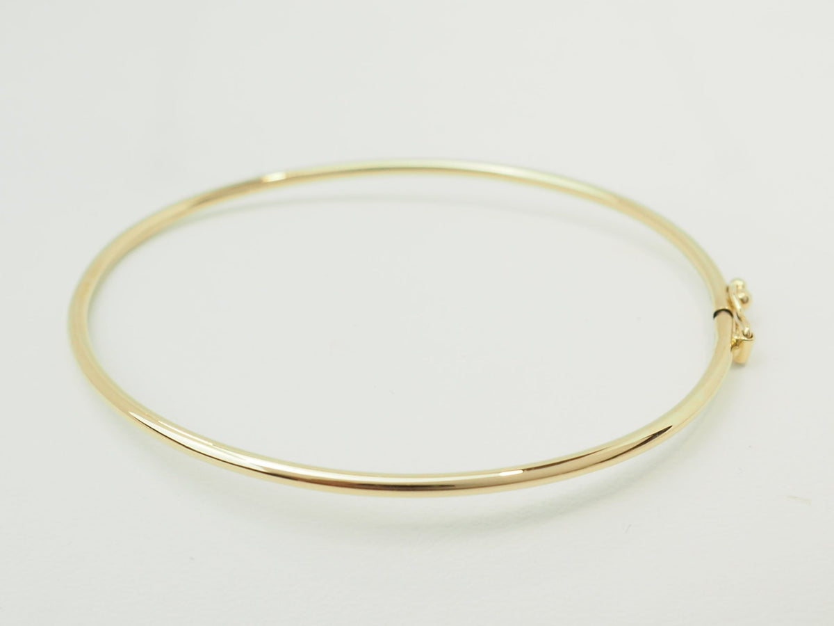 Bracelet jonc flexible L'Aurore en or jaune 18 carats avec fermoir de sécurité sur fond blanc