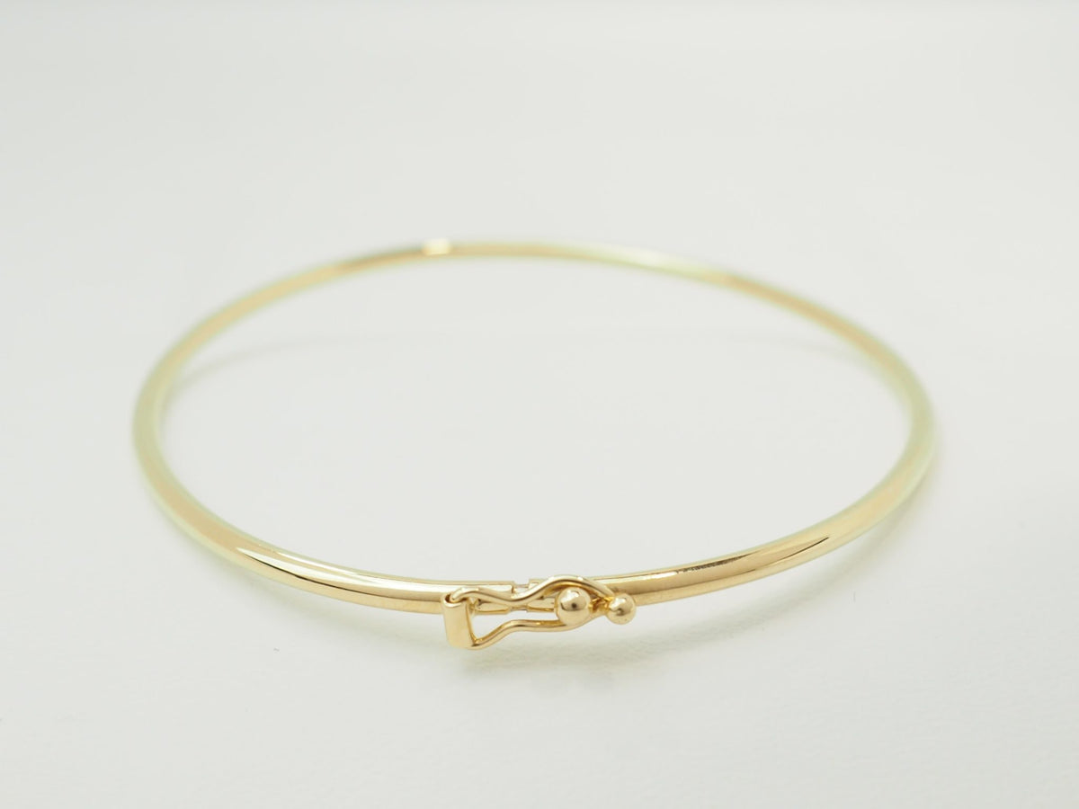 Bracelet jonc flexible L'Aurore en or jaune 18 carats avec fermoir de sécurité sur fond blanc