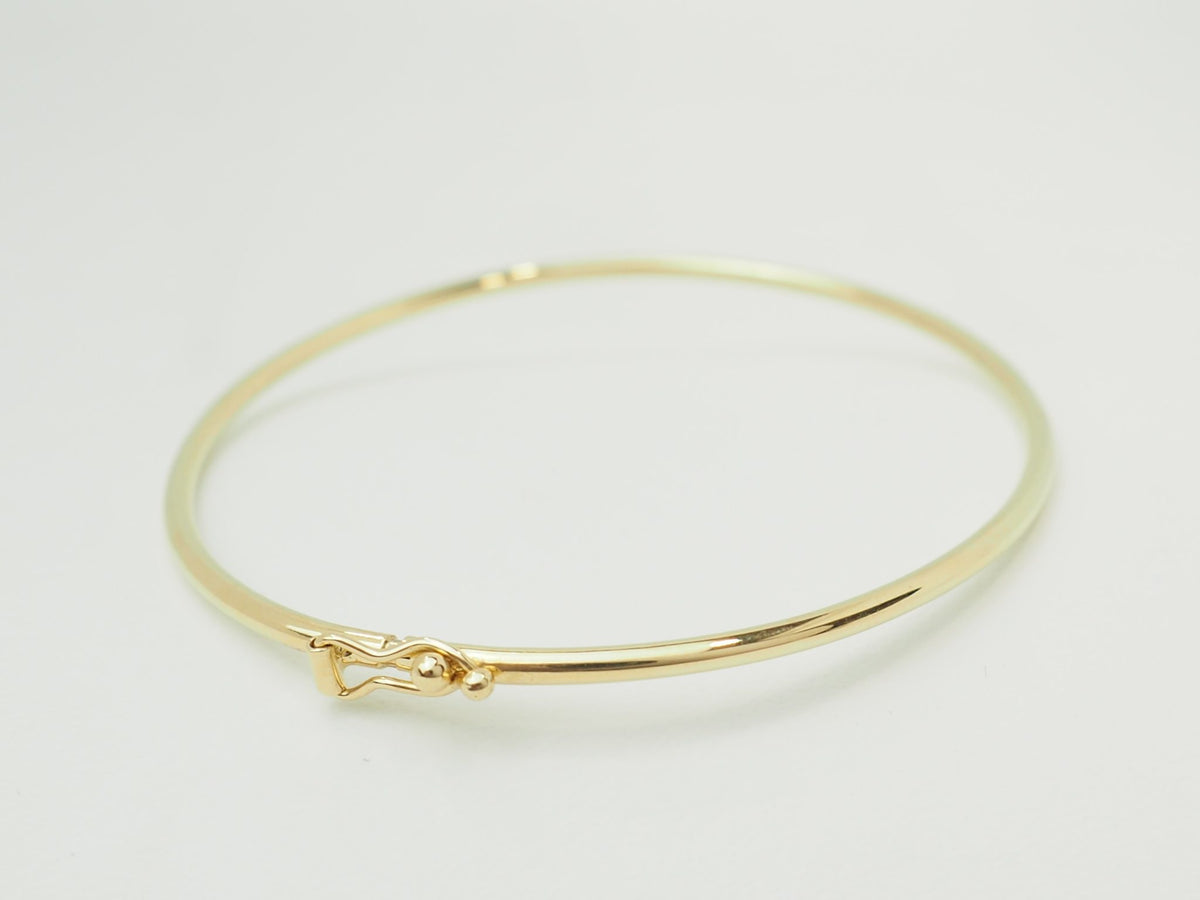 Bracelet jonc flexible L'Aurore en or jaune 18 carats avec fermoir de sécurité sur fond blanc