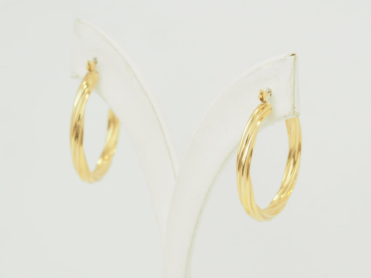 Créoles torsadées L'Aurore en or jaune 18 carats, diamètre 30 mm, finition polie brillante sur présentoir blanc.