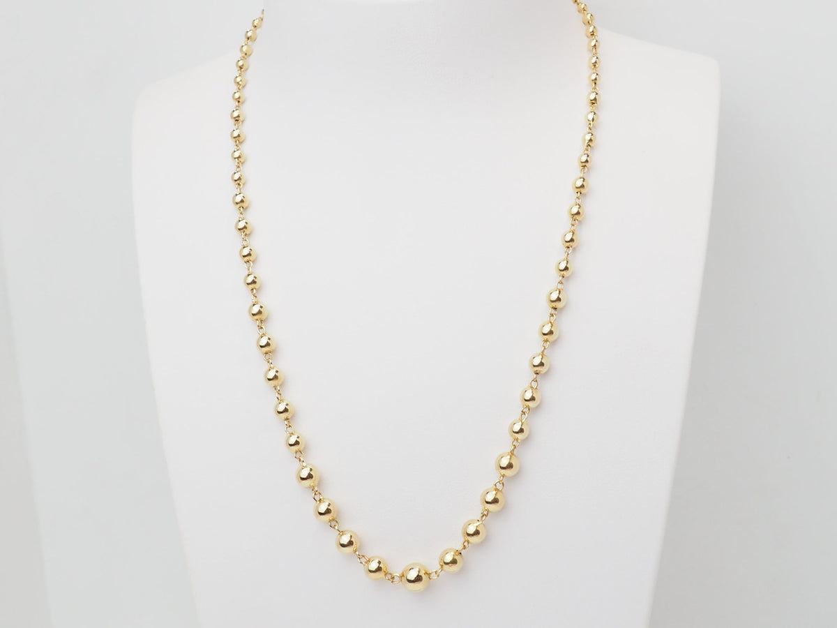 Collier marseillais vintage L'Aurore en or jaune 18 carats avec boules graduées de 2 à 7 mm sur présentoir blanc