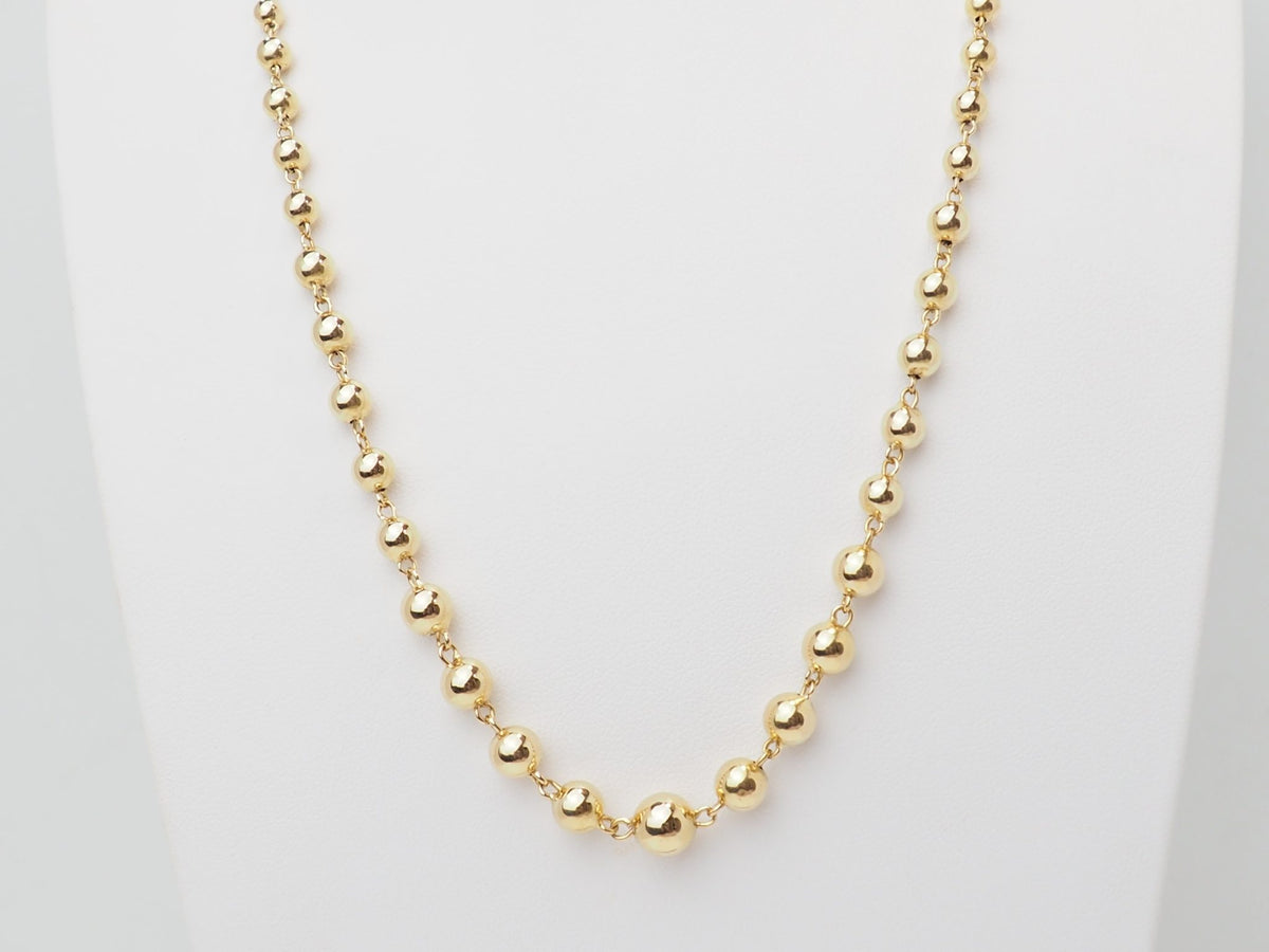 Collier marseillais vintage L'Aurore en or jaune 18 carats avec boules graduées de 2 à 7 mm sur présentoir blanc